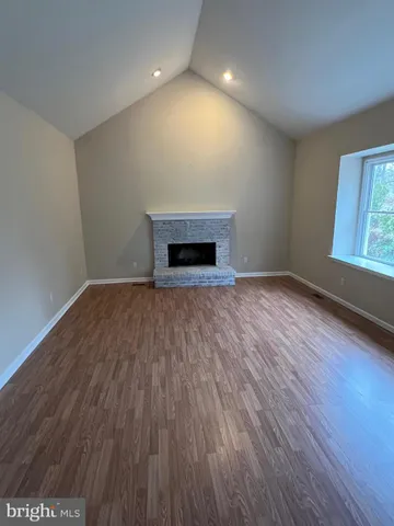 an empty room with wooden floor fireplace and windows