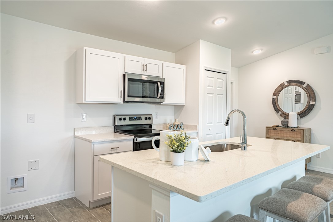 3723 5th Street Southwest Lehigh Acres, FL 33976 - Photo 5 of 9 a kitchen with a sink a stove a microwave and cabinets