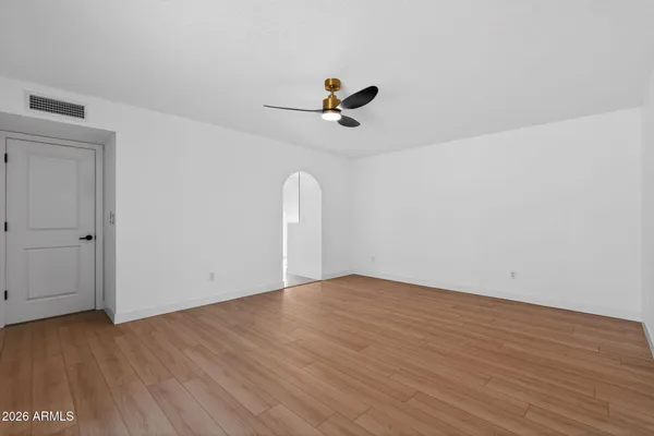an empty room with wooden floor ceiling fan