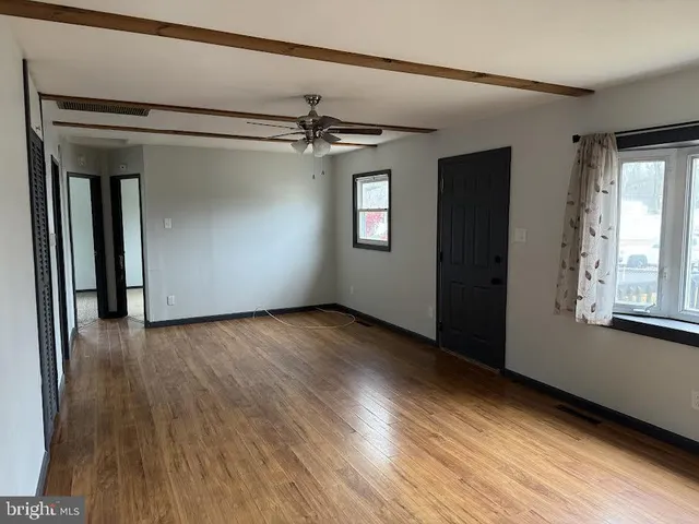 a view of an empty room with wooden floor and a window