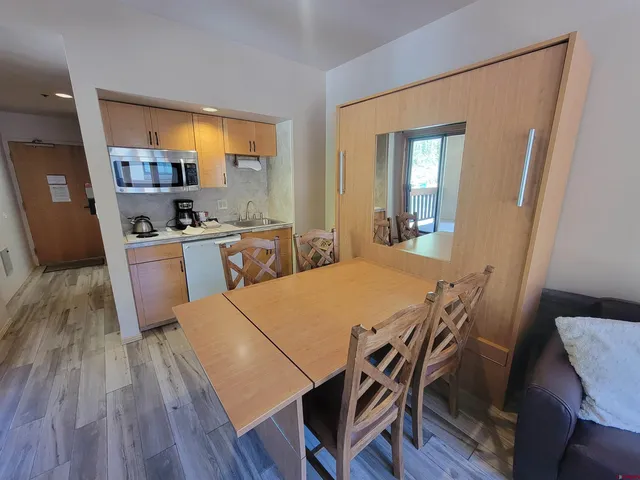 a kitchen with stainless steel appliances a dining table chairs and wooden floor