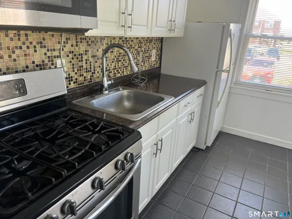a kitchen with granite countertop a stove sink and cabinets
