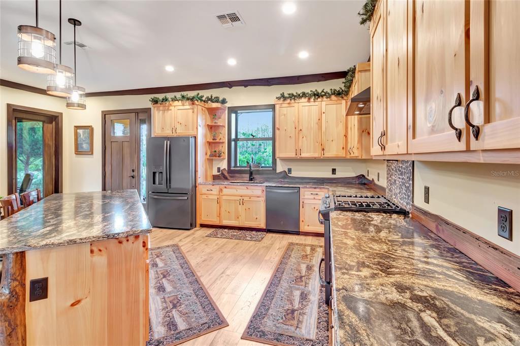 7330 Crabgrass Road St. Cloud, FL 34773 - Photo 11 of 60 a large kitchen with kitchen island a large window a sink and stainless steel appliances