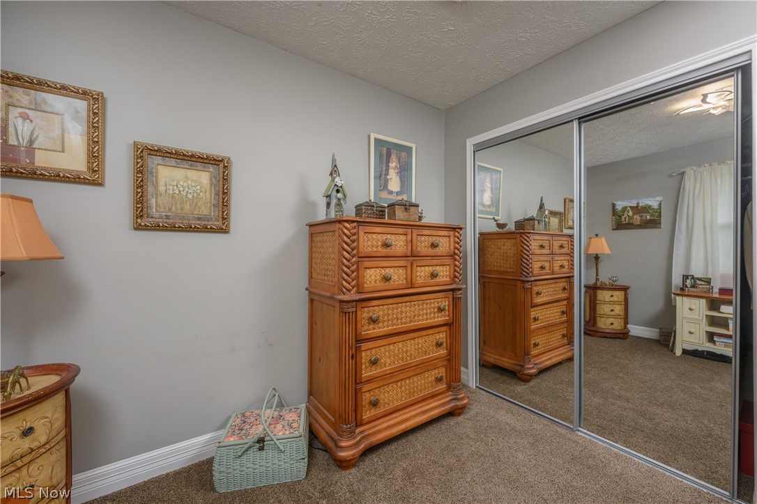 390 Ross Road Waynesburg, OH 44688 - Photo 18 of 30 Bedroom featuring a closet, dark colored carpet, and a textured ceiling