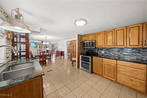 a kitchen with granite countertop a stove a sink and a refrigerator