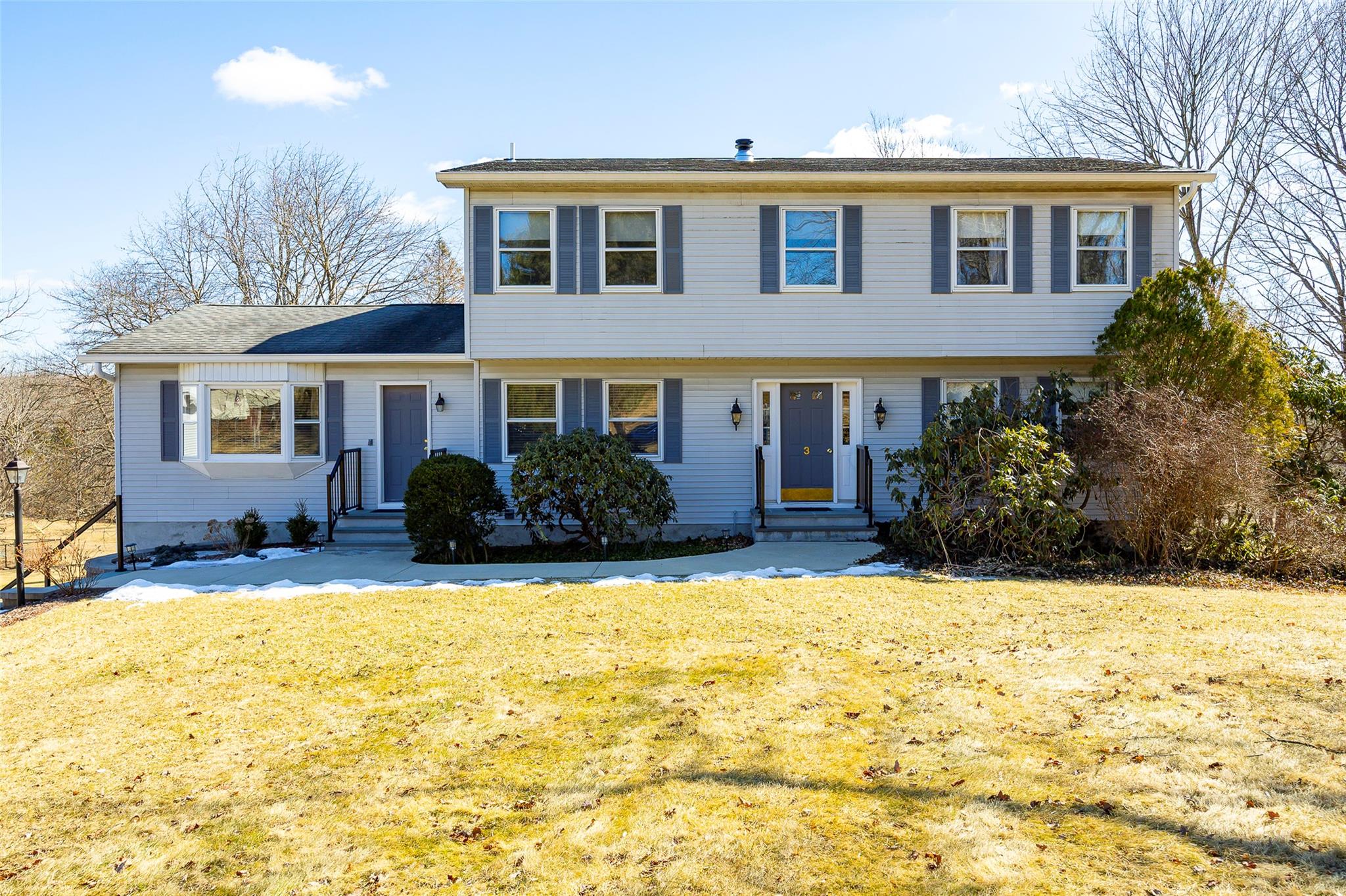 a front view of a house with yard and trees in the background