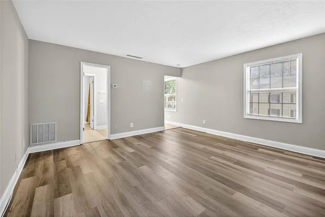 a view of an empty room with wooden floor and a window