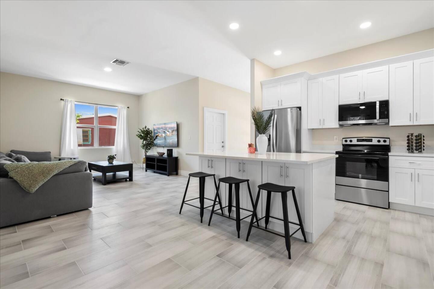 a kitchen with stainless steel appliances granite countertop a stove top oven a sink a dining table and chairs with wooden floor