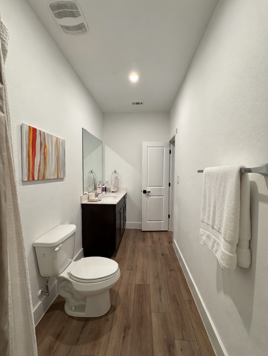 13513 Menard Way Elgin, TX 78621 - Photo 10 of 18 Bathroom with dark wood-style flooring, vanity, and curtained shower