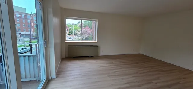 an empty room with wooden floor closet and windows
