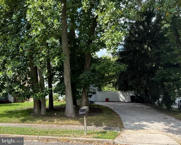 a view of a brick house next to a yard with large trees