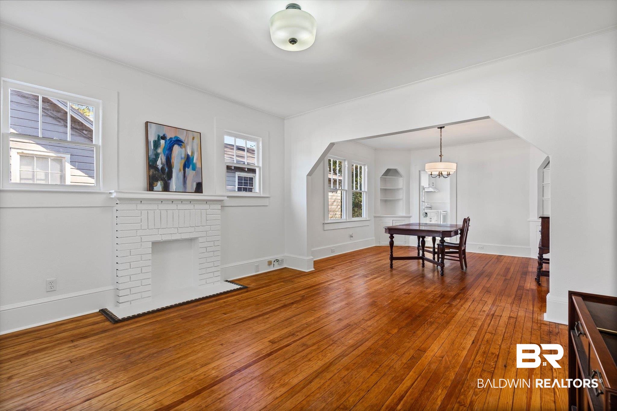 2153 Old Government Street Mobile, AL 36606 - Photo 3 of 23 Dining room featuring wood-type flooring, a brick fireplace, arched walkways, and a chandelier