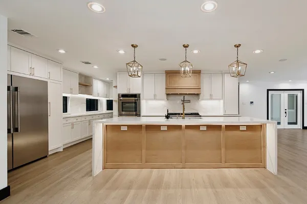 a large kitchen with stainless steel appliances a large counter top a sink and a refrigerator