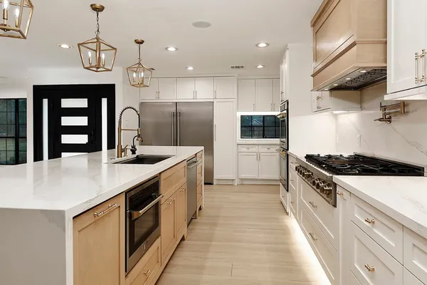 a large kitchen with stainless steel appliances granite countertop a sink a stove and a refrigerator