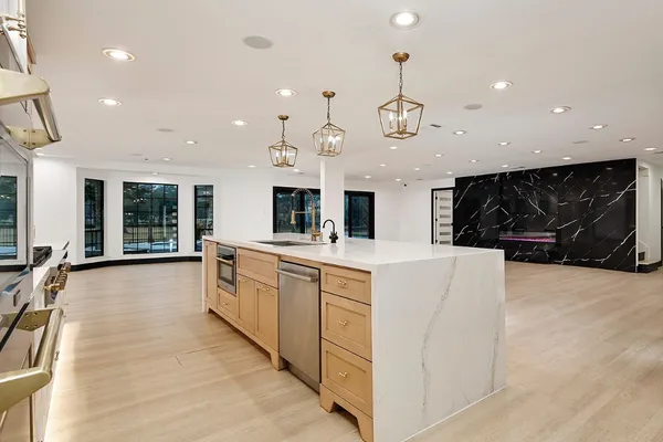 a large white kitchen with a large island oven a stove and a sink