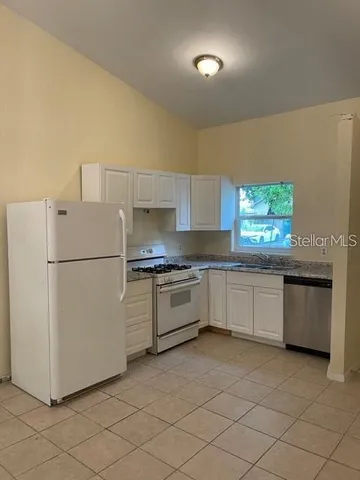 a kitchen with granite countertop white cabinets and white appliances