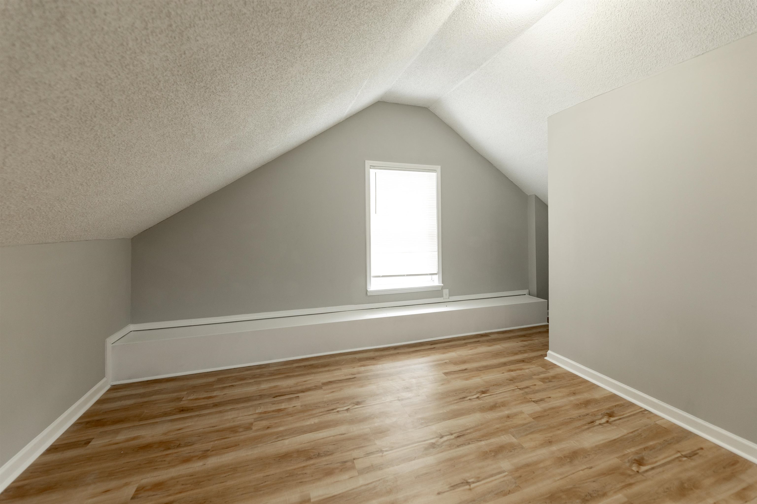 7421 Richmond Road Memphis, TN 38125 - Photo 31 of 39 Attic space featuring wood-finish flooring, light grey painted walls, white baseboards, and a window with white trim
