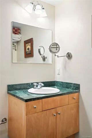 a bathroom with a granite countertop sink and a white cabinets