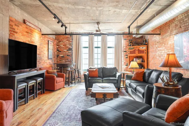 a living room with furniture a flat screen tv and floor to ceiling window
