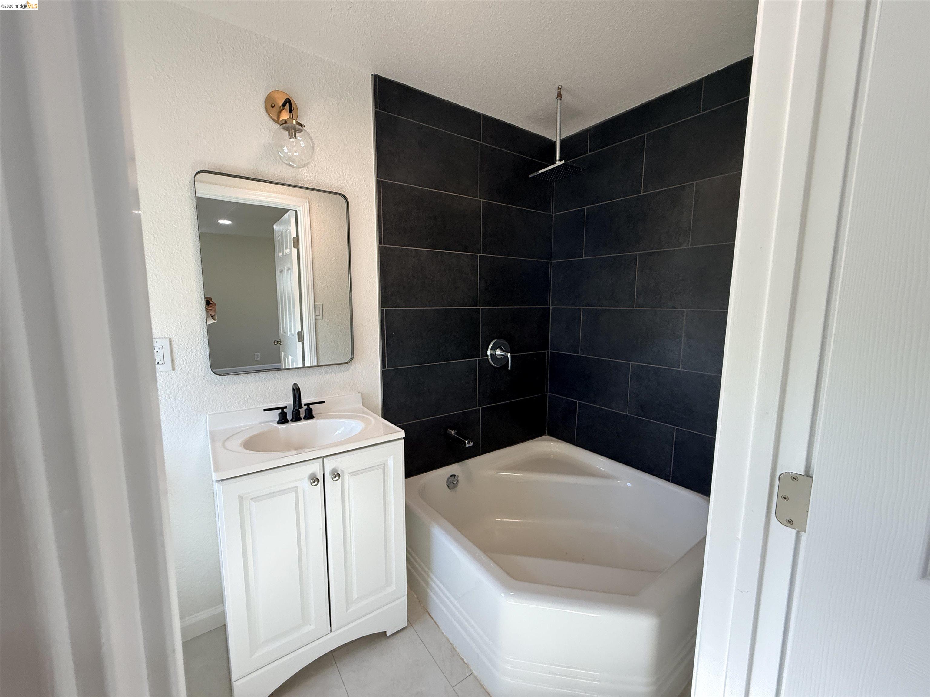 321 Benicia Road Vallejo, CA 94590 - Photo 21 of 48 Full bath featuring vanity, a combined bath / shower with rainfall shower, a textured wall, and light tile patterned floors