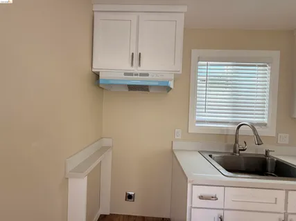 a kitchen with white cabinets and sink