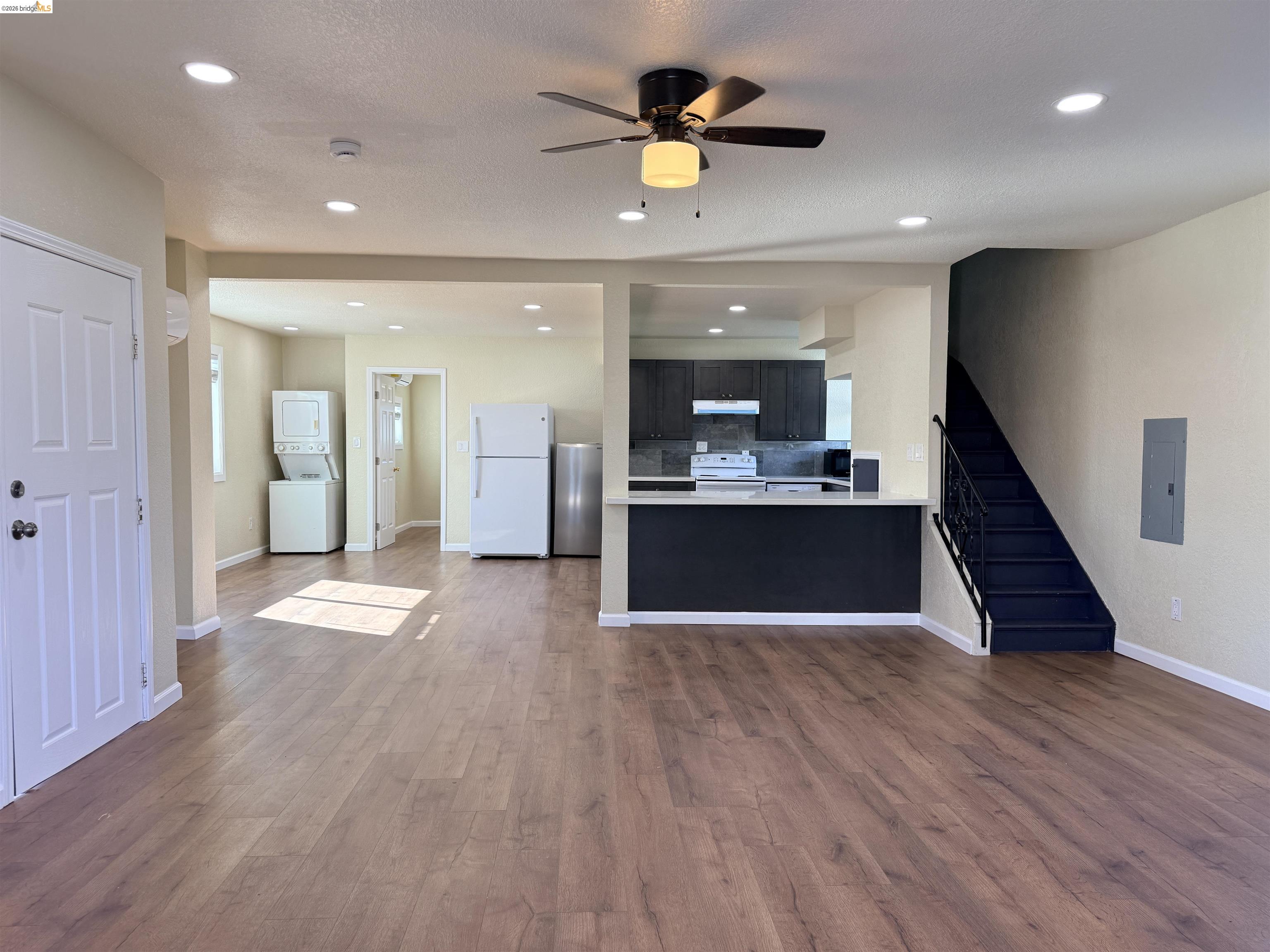 321 Benicia Road Vallejo, CA 94590 - Photo 6 of 48 Unfurnished living room with stacked washing machine and dryer, a ceiling fan, dark wood-type flooring, electric panel, and recessed lighting