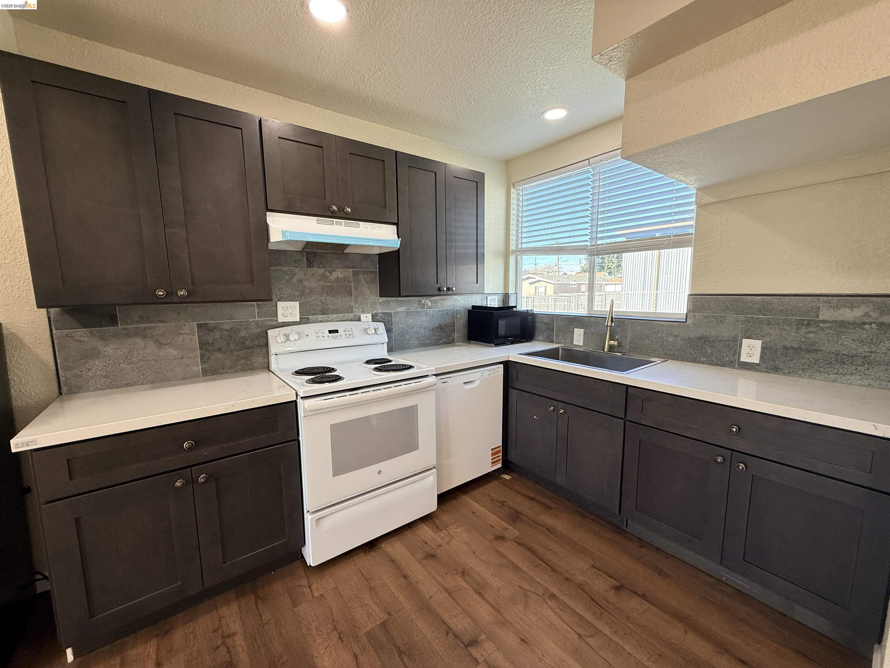 321 Benicia Road Vallejo, CA 94590 - Photo 8 of 48 Kitchen with white appliances, dark wood finish cabinetry, a textured wall, dark wood-style floors, and a textured ceiling