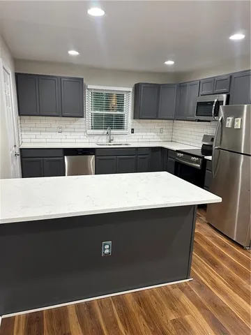 a kitchen with stainless steel appliances a refrigerator a sink a stove a microwave and wooden cabinets