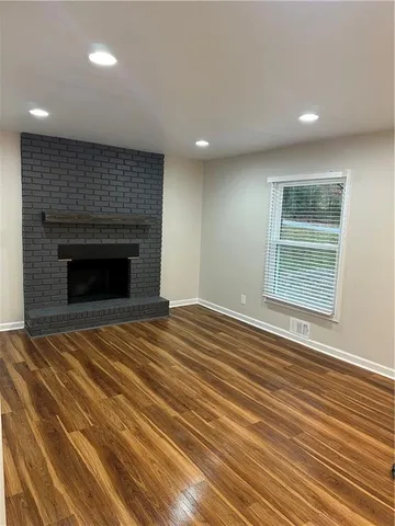 an empty room with wooden floor fireplace and windows