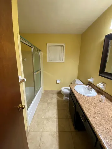 a bathroom with a granite countertop sink a toilet and a tub