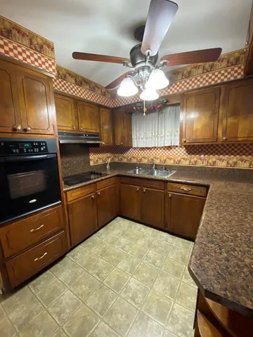 a kitchen with granite countertop a sink cabinets and stainless steel appliances