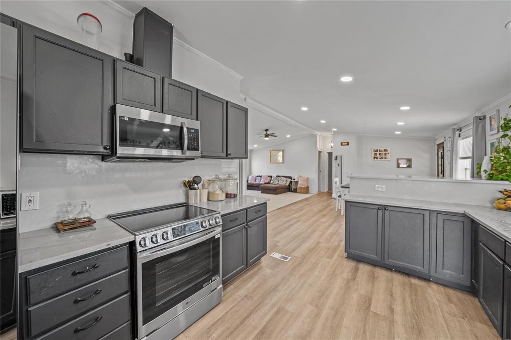 169 Cumberland Trail Bridgeport, TX 76426 - Photo 5 of 23 a large kitchen with stainless steel appliances granite countertop a stove a sink dishwasher and a microwave oven with wooden floor
