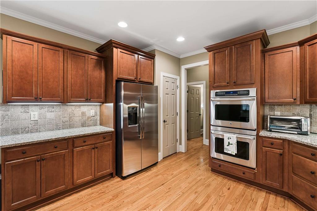 5148 Stefan Ridge Way Buford, GA 30519 - Photo 11 of 39 a kitchen with stainless steel appliances granite countertop a refrigerator a stove top oven and sink with wooden floor