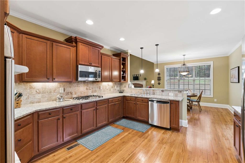 5148 Stefan Ridge Way Buford, GA 30519 - Photo 13 of 39 a large kitchen with wooden floors and stainless steel appliances