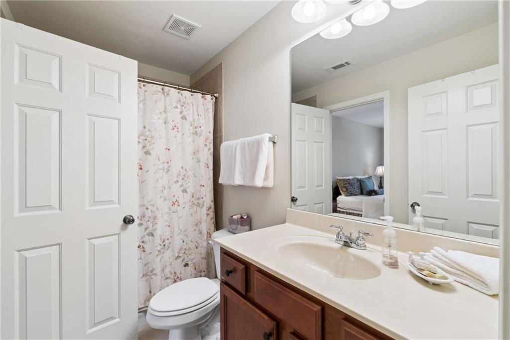 5148 Stefan Ridge Way Buford, GA 30519 - Photo 32 of 39 a bathroom with a granite countertop sink toilet a mirror a vanity and shower