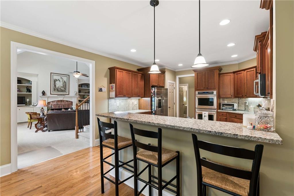 5148 Stefan Ridge Way Buford, GA 30519 - Photo 9 of 39 a kitchen with stainless steel appliances kitchen island granite countertop a table chairs sink and cabinets