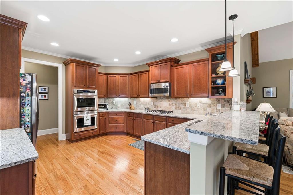 5148 Stefan Ridge Way Buford, GA 30519 - Photo 10 of 39 a large kitchen with stainless steel appliances kitchen island granite countertop a refrigerator a stove a sink a dining table and chairs with wooden floor