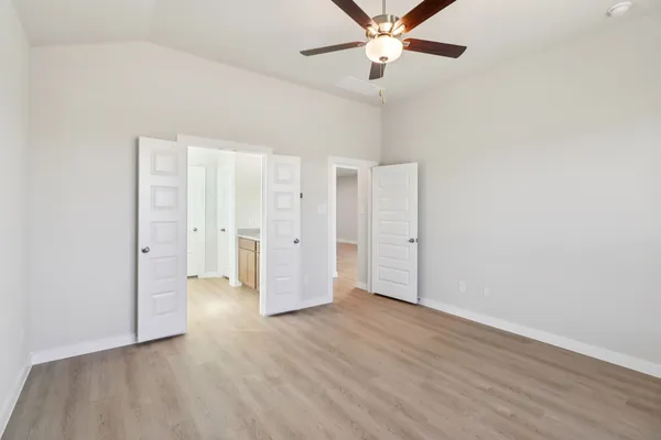 an empty room with wooden floor and ceiling fan