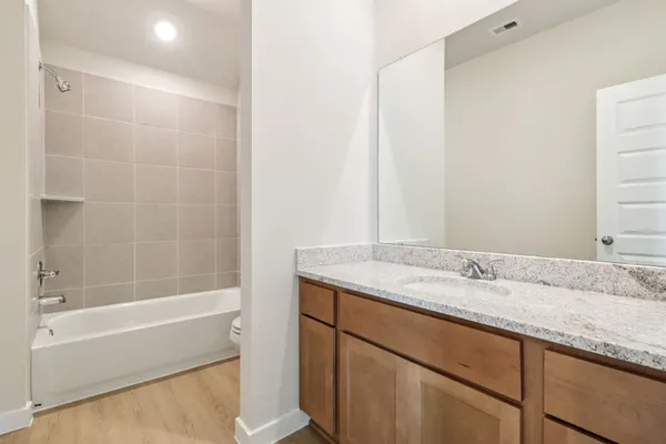 a bathroom with a granite countertop sink and a bathtub