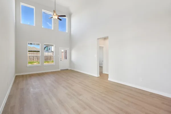 an empty room with wooden floor cabinet and windows