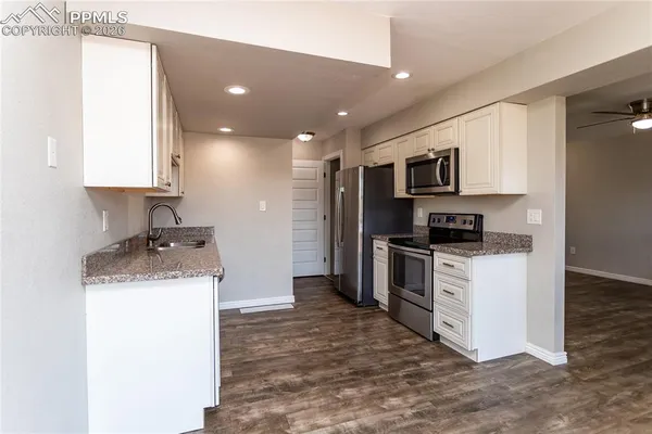 a kitchen with stainless steel appliances granite countertop a stove top oven a sink and a refrigerator