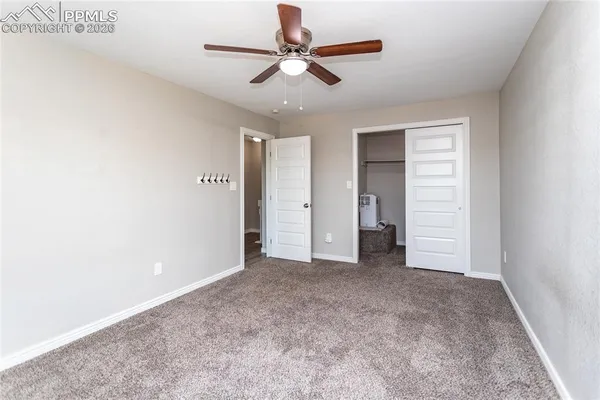 an empty room with closet and a ceiling fan