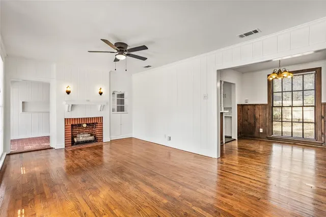 an empty room with wooden floor fireplace and windows