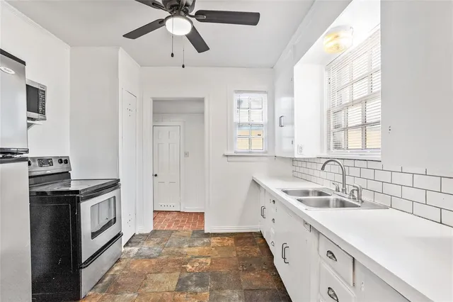 a kitchen with granite countertop a sink stainless steel appliances a window and a counter top space