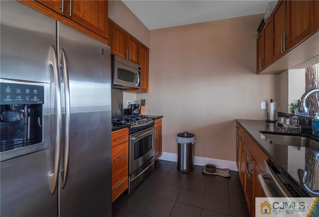 1 Spring Street, Unit 2204 New Brunswick, NJ 08901 - Photo 12 of 29 a kitchen with stainless steel appliances granite countertop a refrigerator a stove and a sink with wooden floor