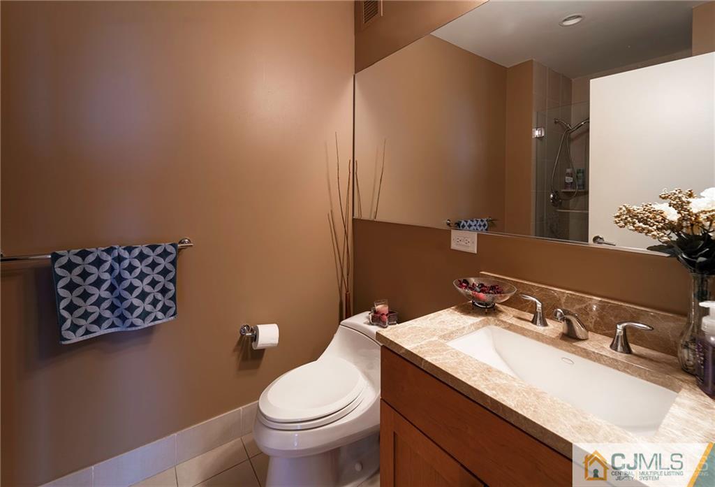 1 Spring Street, Unit 2204 New Brunswick, NJ 08901 - Photo 18 of 29 a bathroom with a granite countertop sink mirror vanity and toilet