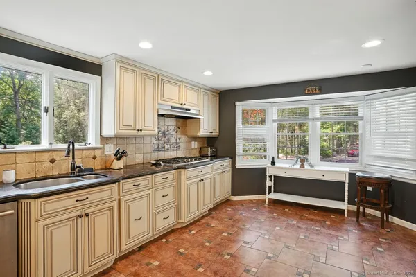 a kitchen with kitchen island granite countertop a sink and white cabinets