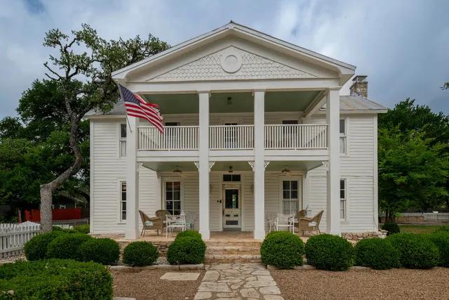 a front view of a house with a yard and potted plants
