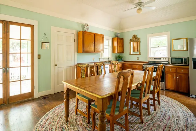 a dining hall with stainless steel appliances granite countertop a stove a sink a dining table and chairs with wooden floor