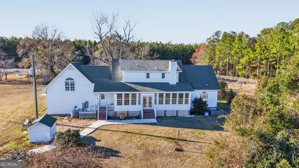 an empty room with chandelier fan and windows